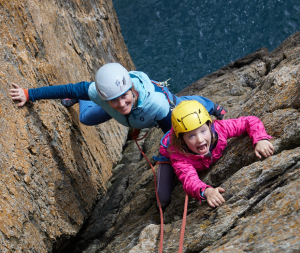 Mother and daughter climbing up a sea cliff