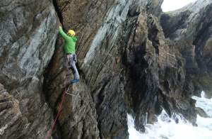 A lead climber on sea cliff just above the tide